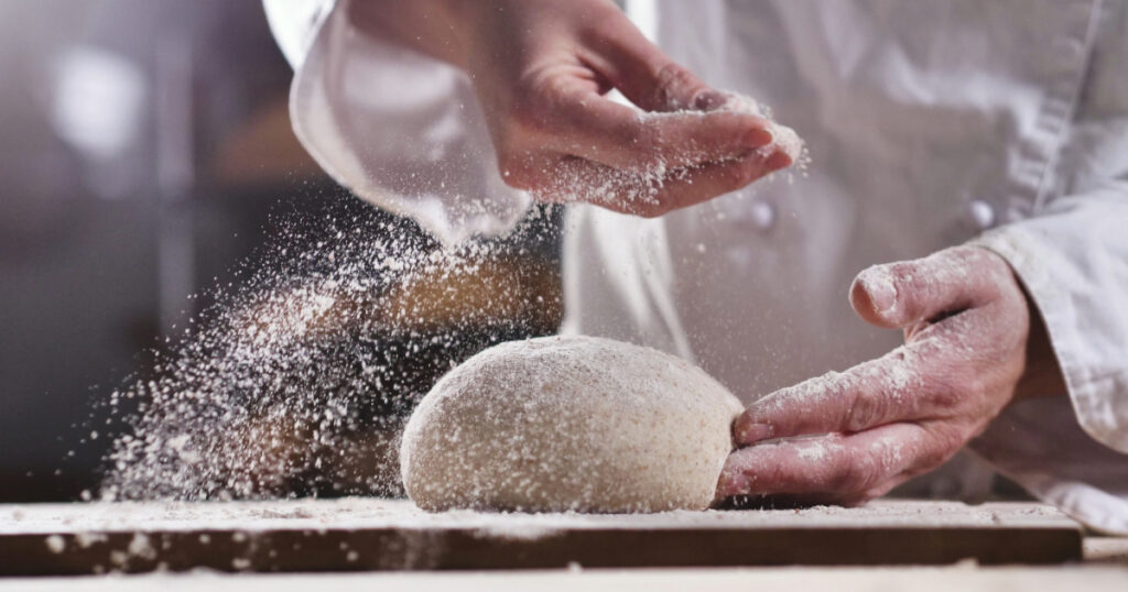 Shutterstock An experienced chef in a professional kitchen prepares the dough with flour
