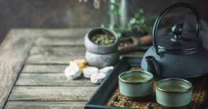 Still-life of japanese healthy green tea in a small cups and teapot over dark background