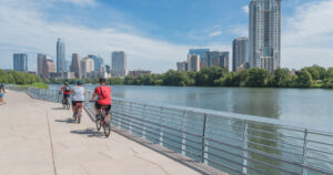 People biking along Colorado River waterfront boardwalk near downtown Austin, Texas