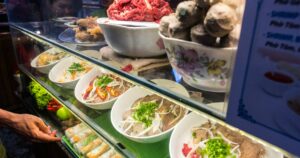 Ho Chi Minh, Vietnam - April 28, 2018: Street food stand with plates filled with soup pho ingredients (including boiled and raw meat) ready to be used. In Street Food Market at Ben Thanh Market area.