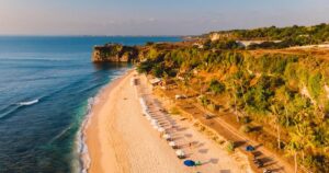 Aerial view of beach with turquoise ocean and beach umbrellas. Balangan, Bali