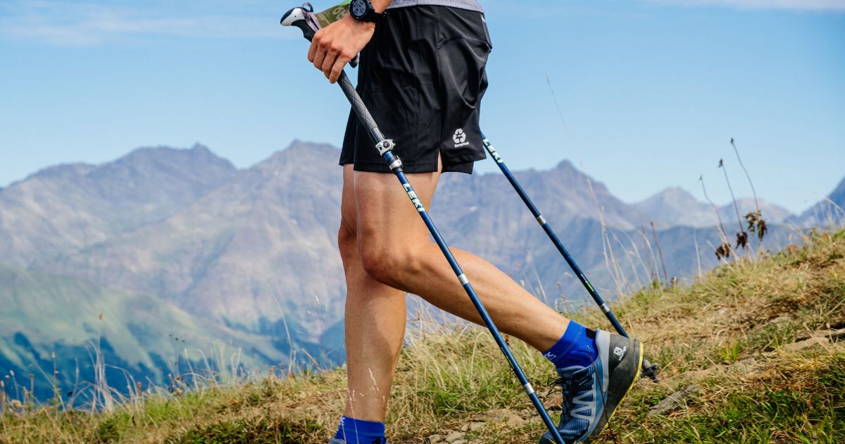 Rosa Khutor, Russia - September 10, 2022: legs man with trekking poles descent from mountain in Rosa Wild Trail
