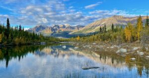 A symmetrical reflection shot on the lake in Wrangell, St Elias National Park, Alaska, mountain tops in the background, and blue sky above