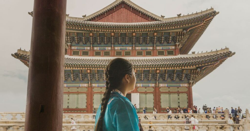 Shutterstock A girl in a traditional hanbok looking at Geunjeongjeon Hall of Gyeongbokgung Palace in Seoul