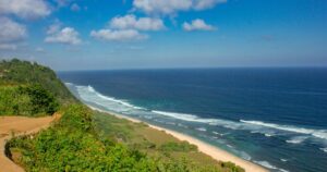 Top view of empty Nyang Nyang Beach in Bali with blue sky, clouds, and sun light