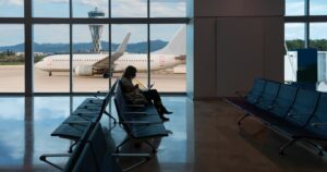 Silhouette of young woman working on laptop and waiting for flight in the Airport - El Prat-Barcelona airport. This airport was inaugurated in 1963 - Barcelona, Spain