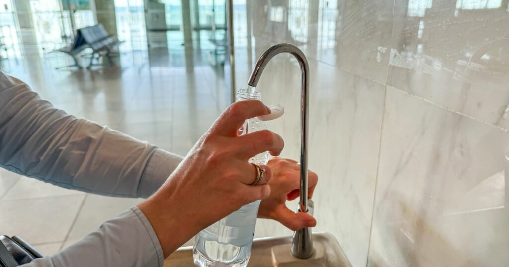 Shutterstock A person filling a reusable water bottle at an airport terminal