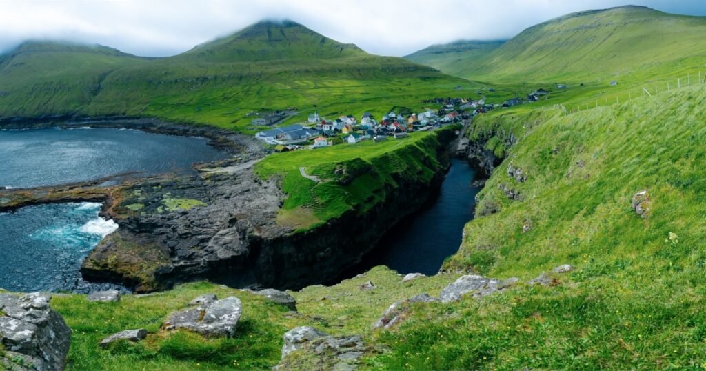 Panoramic top view for the village Gjogv sea-filled gorge and village on Eysturoy in the Faroe Islands. Denmark, North Europe