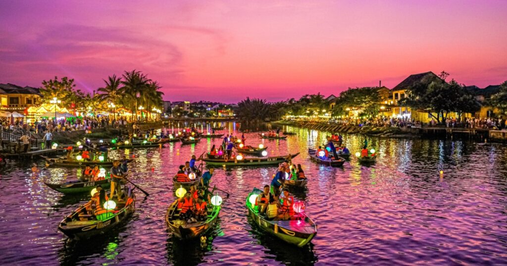 Scenic view of Thu Bon River and vintage buildings in Hoi An during sunset. 
