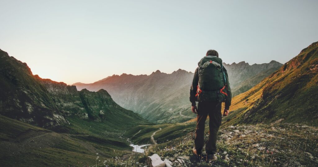 Shutterstock Man hiking at sunset mountains with heavy backpack