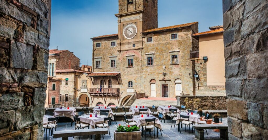 Shutterstock Cortona Communal Palace with renaissance tower clock seen from a narrow street in the historic center in Tuscany