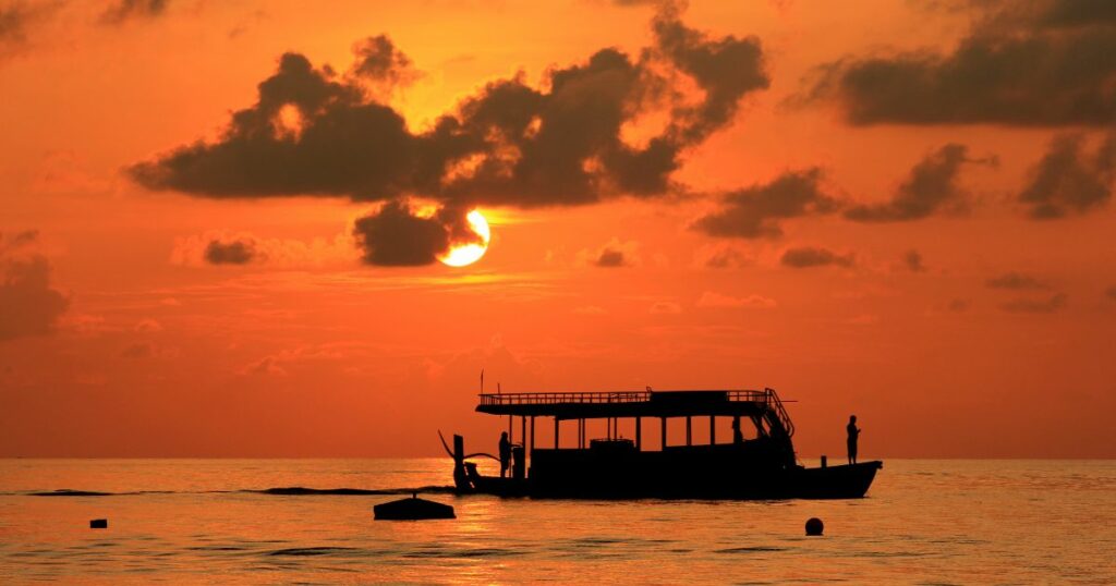 Shutterstock A sunset cruise boat passes by the Maafushi Beach