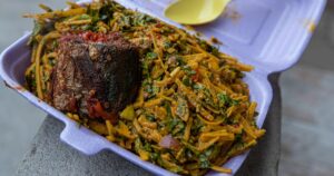 A close up shot of a plate of african salad (Abacha and Ugba) with a piece of fried croaker fish