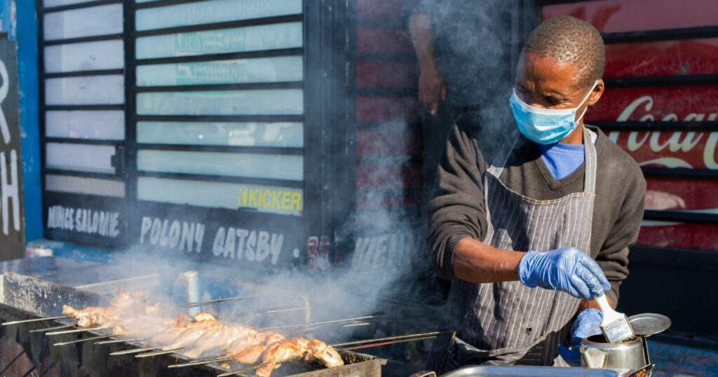 African street food vendor putting oil on his grill