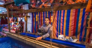 Local artisan weaving with traditional frame and creating handmade textile in old Medina market