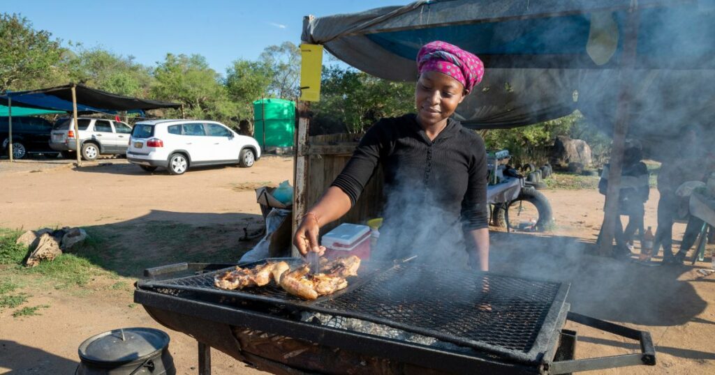 African woman grilling some chicken at her street food stall
