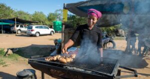 African woman grilling some chicken at her street food stall
