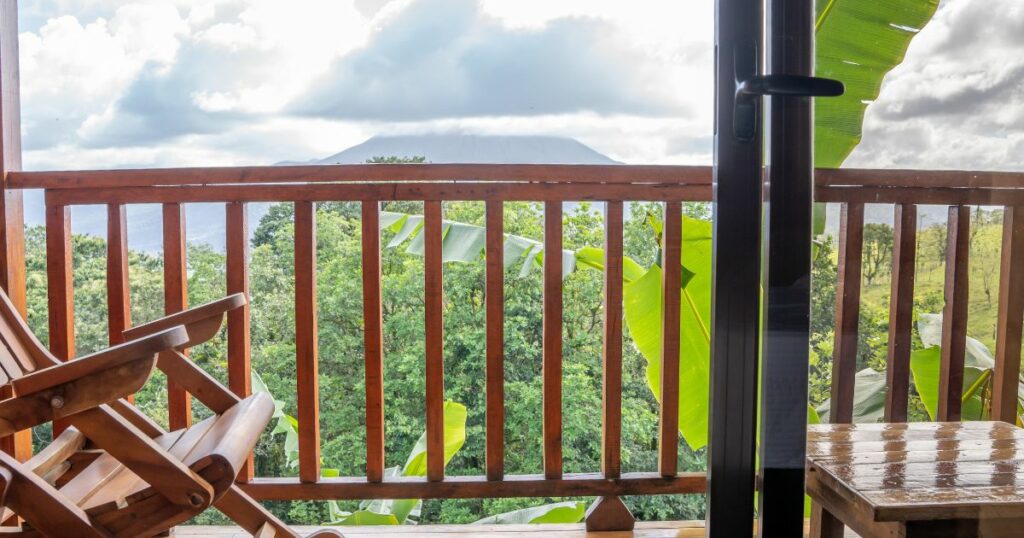 Shutterstock Views of the jungle and a volcano from the terrace of a rustic hotel with a wooden chair and table