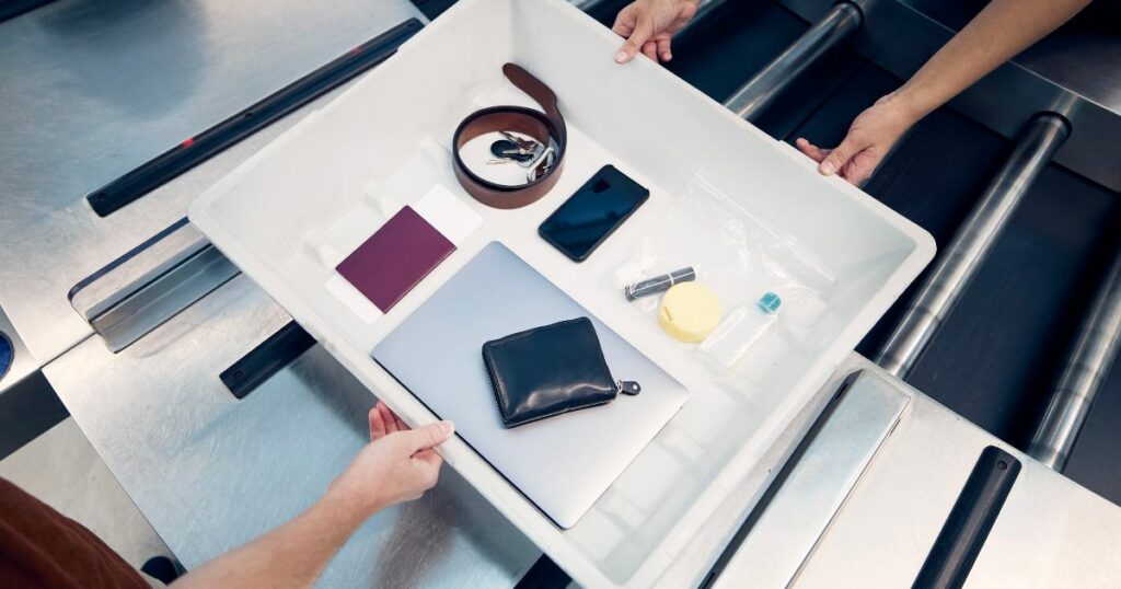 Shutterstock Personal Items, liquids, and laptop in container during control at airport security check before flight