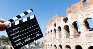 Movie clapper board in front of Coliseum monument in Rome, hands holding film slate defocused background italy