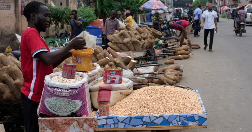 A man selling staple foods stands by his stall as he awaits customers in Lagos