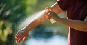 Woman applying insect repellent on her arm outdoors. Skin protection against tick and mosquito bite