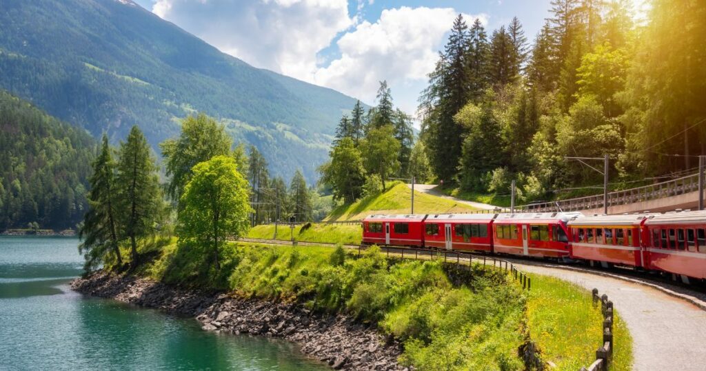 Shutterstock Red train moving along lake in beautiful mountain landscape in Switzerland