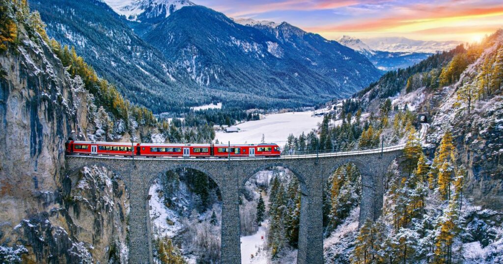 Shutterstock Aerial view of Train passing through famous mountain in Filisur, Switzerland. Landwasser Viaduct world heritage with train express in Swiss Alps snow winter scenery.