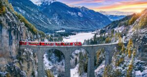 Aerial view of Train passing through famous mountain in Filisur, Switzerland. Landwasser Viaduct world heritage with train express in Swiss Alps snow winter scenery.