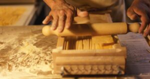 Chef making fresh pasta on a pasta guitar, horizontal