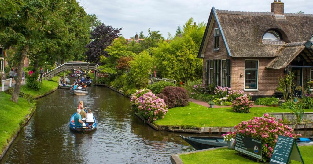 Shutterstock GIETHOORN, NETHERLANDS - AUGUST 01 2017: Unknown visitors in the sightseeing boating trip in a canal in Giethoorn. The beautiful houses and gardening city is know as "Venice of the North".