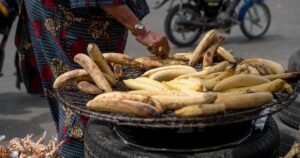 A woman roasting plantain on a grill in Lagos, Nigeria