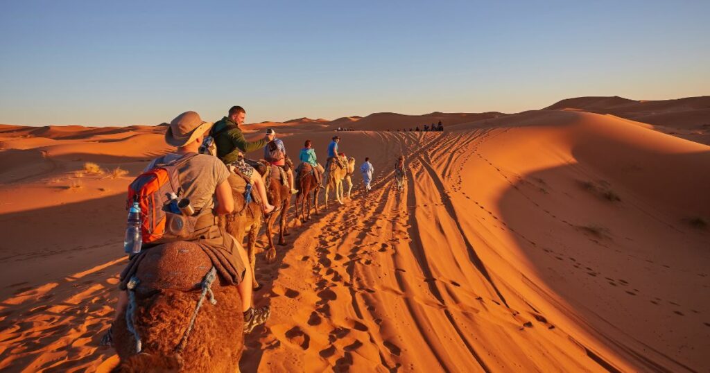 Shutterstock Tourists riding camels, smiling, in the Sahara Desert, Morocco