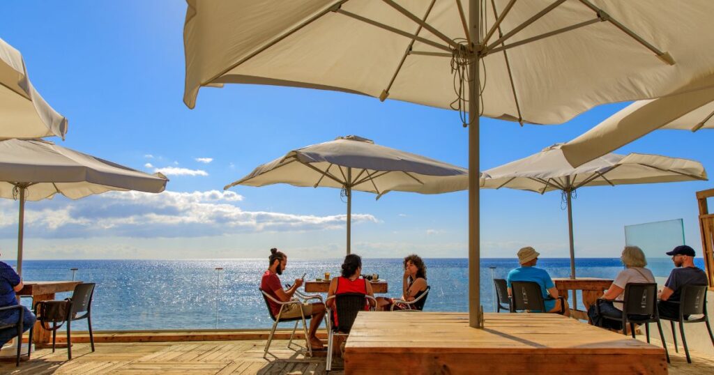 Shutterstock People at a sunny terrace with umbrellas near the sea in Canary Islands