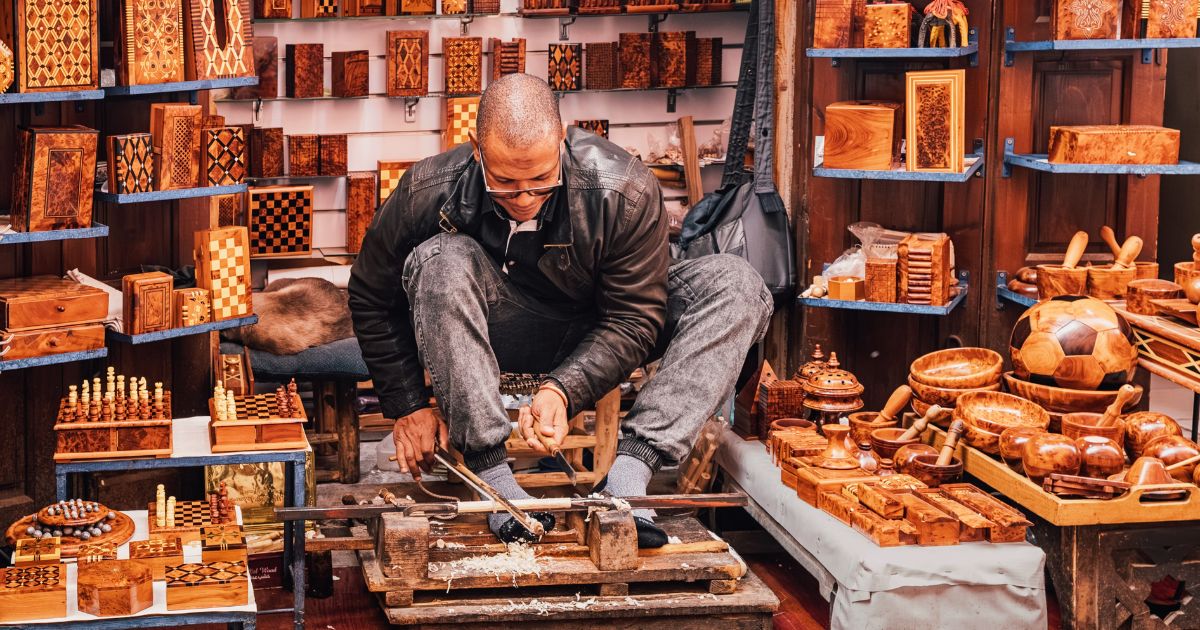 Moroccan artisan working wood with traditional tools, creating handcrafted souvenirs in a medina souk