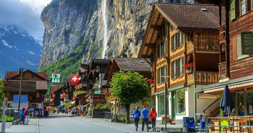 Shutterstock Spectacular principal street of Lauterbrunnen with shops,hotels,terraces,swiss flags and stunning Staubbach waterfall in background,Bernese Oberland,Switzerland,Europe