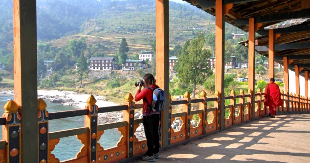 Female tourist taking photograph, An antique wooden bridge at Punakha Dzong Monastery Bhutan