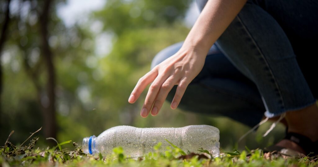 Woman picking up plastic bottle from a public park