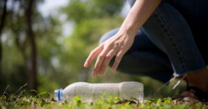 Woman picking up plastic bottle from a public park