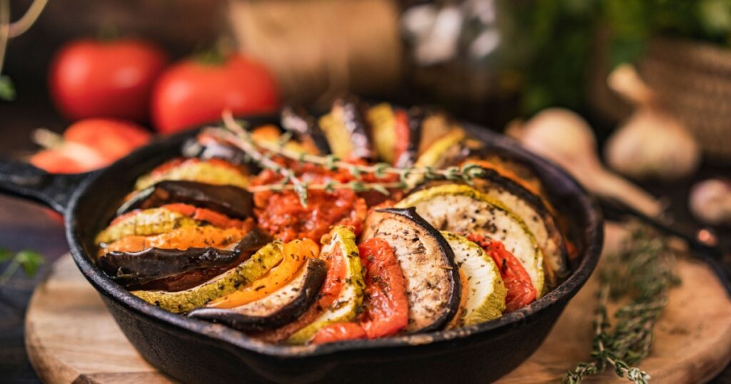 Ratatouille made of zucchini, eggplants, peppers, onions, garlic and tomatoes slices with aromatic herbs
