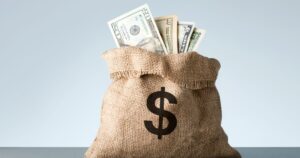 Burlap with dollar banknotes on gray background.