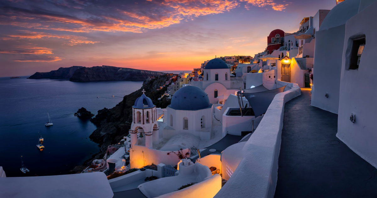 Beautiful view to the three blue domed churches in the village of Oia, Santorini, Greece, during dusk without people