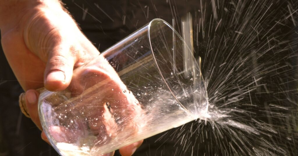 Escanciar sidra, detail of a hand holding a glass while serving cider, Asturias, Spain