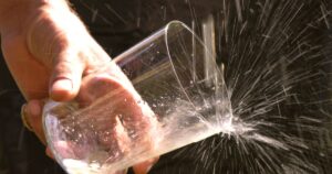 Escanciar sidra, detail of a hand holding a glass while serving cider, Asturias, Spain