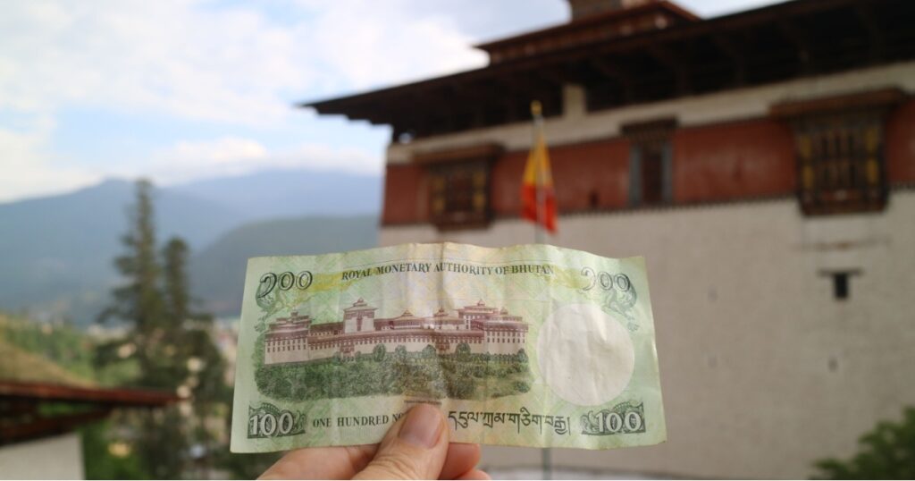 Bhutanese ngultrum (BTN) currenct note in front of monastery