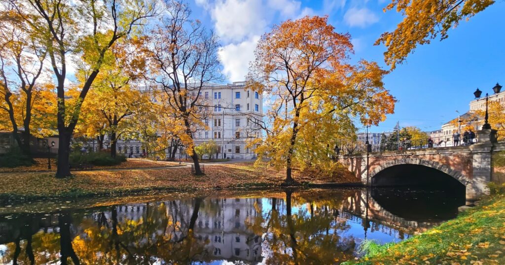 Bright colours of early autumn in Kronvalda Park with green lawns near the city canal in Riga Old Town, capital of Latvia.