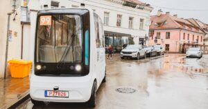 White electric self-driving bus vehicle in Vilnius capital city Uzupis area street traffic.