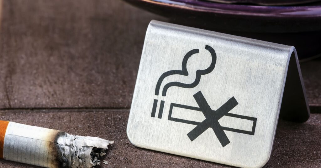 NO Smoking sign and cigarette burned on concrete table.