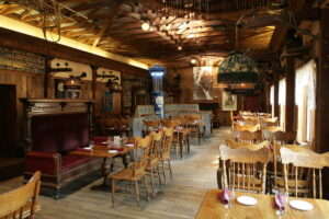 Interior of The Pump House Restaurant in Fairbanks, Alaska, featuring rustic wooden décor, vintage memorabilia, and set dining tables with wooden chairs and red napkins. Historic details and antique furnishings reflect the building’s gold rush heritage.