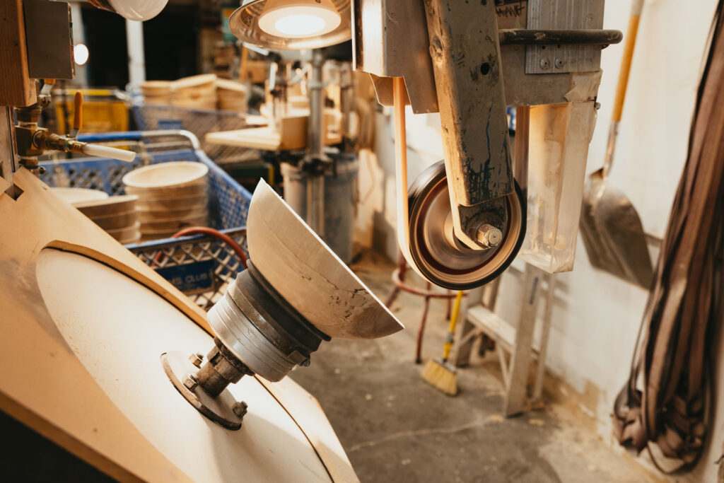 Wooden bowl mounted on a lathe during the sanding process inside the Great Alaska Bowl Company workshop.